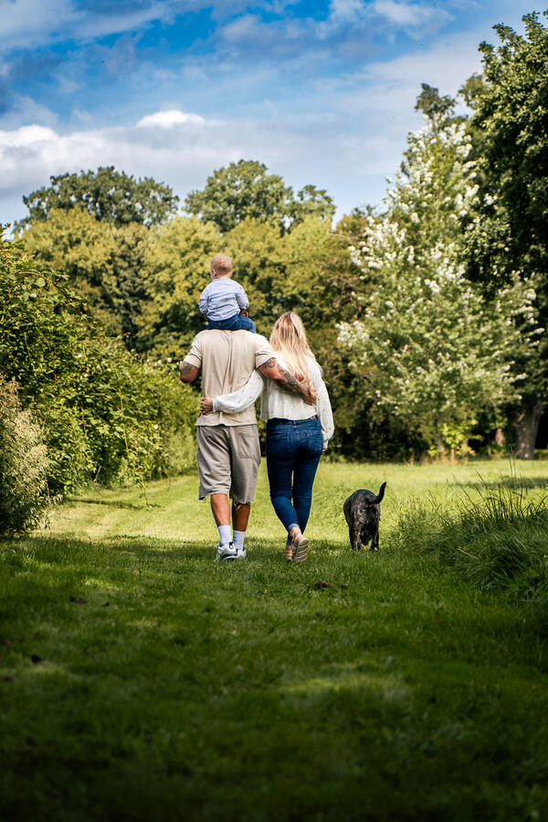 Familie mit Kind und Hund spaziert gemeinsam auf einem Waldweg – authentisches Outdoor-Familienshooting.