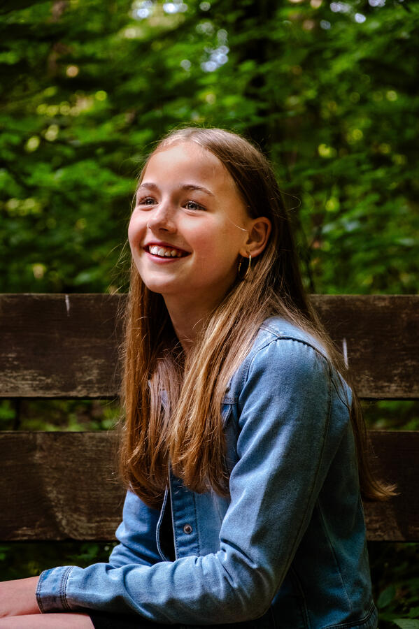 Portrait eines Mädchens mit langen Haaren, lächelnd im Sonnenlicht – natürliche Outdoor-Aufnahme