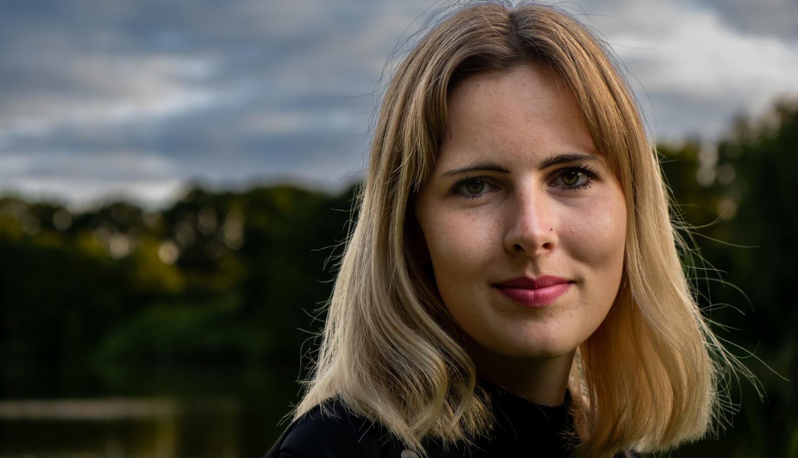 Dieses Portrait wurde in den Abendstunden an einem ruhigen See aufgenommen. Die weiche Lichtstimmung und der direkte Blick der Person erzeugen eine besondere Nähe, ohne aufdringlich zu wirken.