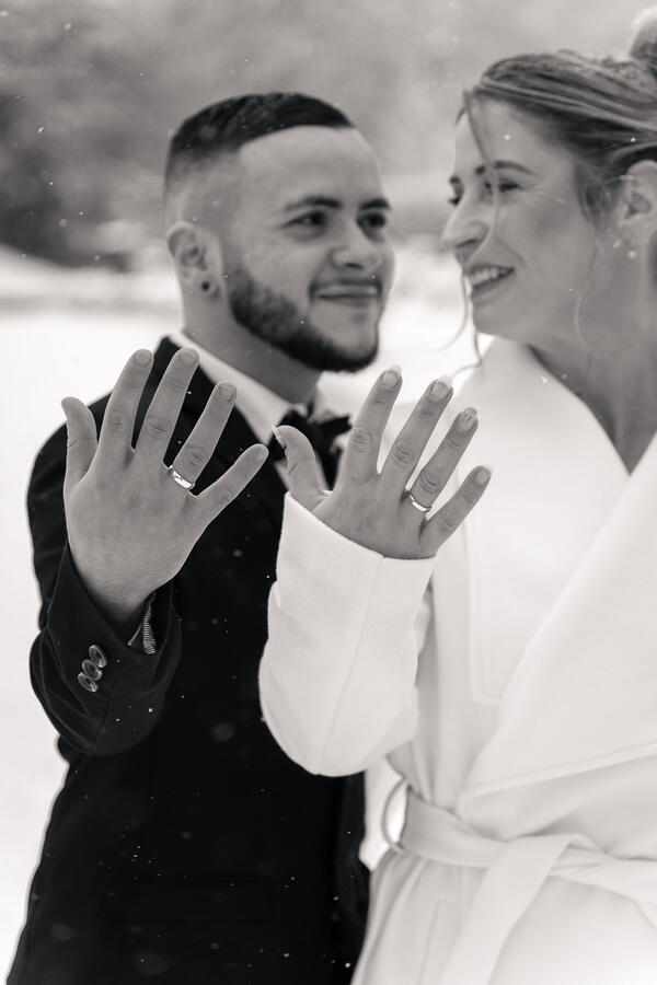 Braut und Bräutigam zeigen ihre Eheringe bei einer Winterhochzeit in Ahrensburg, Schwarz-Weiß-Hochzeitsfotografie.