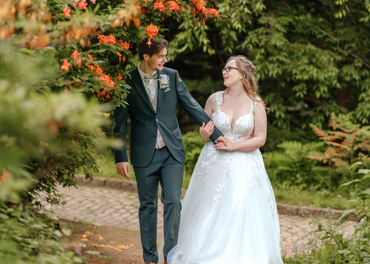 Brautpaar spaziert glücklich am alten Botanischen Garten in Kiel – Hochzeitsfotograf Schleswig Holstein für natürliche Hochzeitsfotos