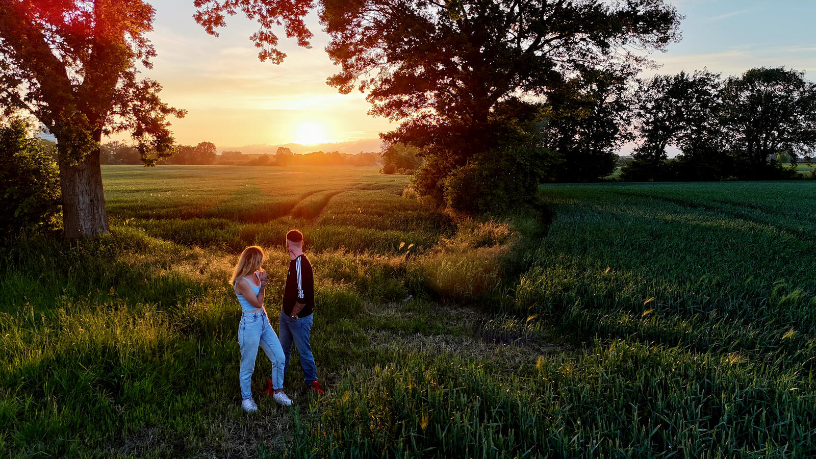 Romantisches Paarshooting bei Sonnenuntergang mit Drohne – natürliche Luftaufnahme zur goldenen Stunde auf dem Feld in Norddeutschland