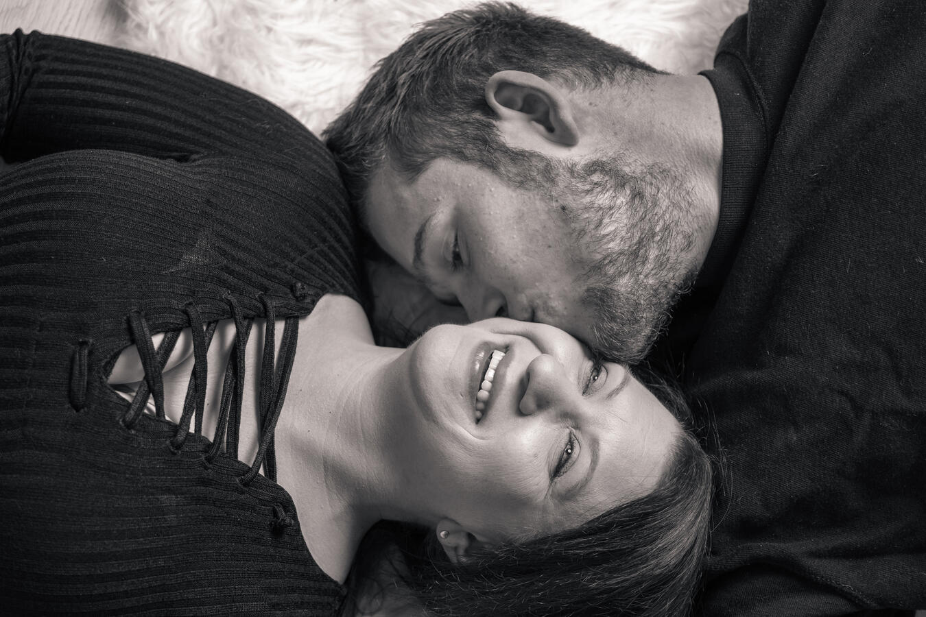 Zwei Personen liegen eng nebeneinander und schauen sich ruhig und liebevoll an, aufgenommen aus der Vogelperspektive.