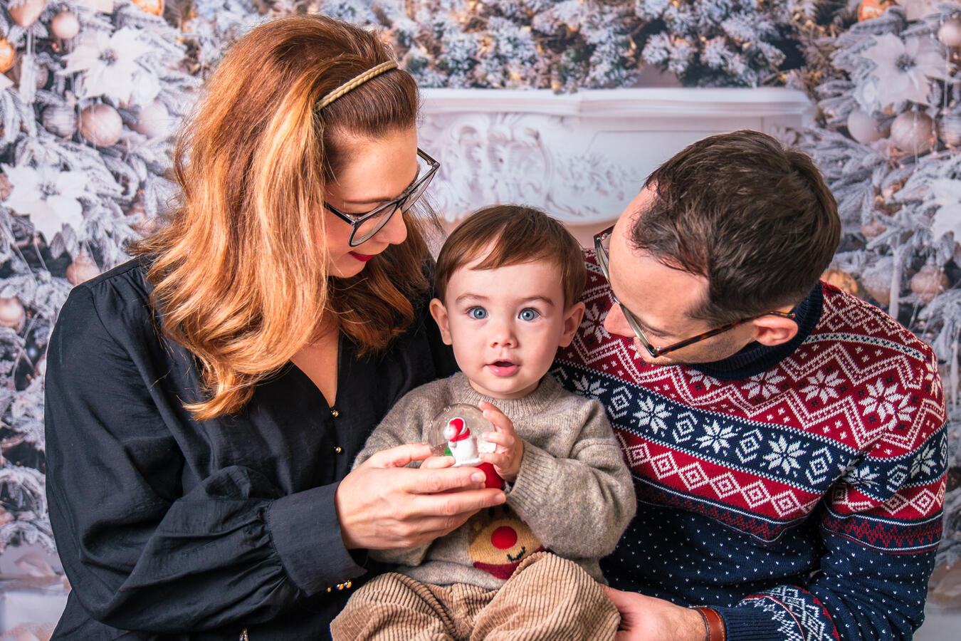 Ein liebevolles Familienfoto: Mutter, Vater und Kind sitzen eng beieinander und teilen einen warmen, emotionalen Moment. Perfekt für authentische Familienreportagen und natürliche Lifestyle-Fotografie, Weihnachtsshooting