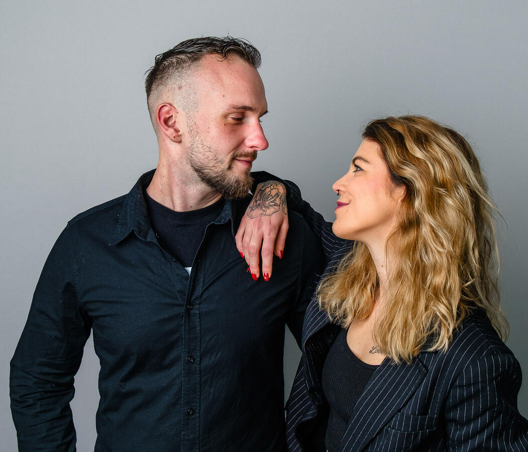 Paarportrait eines Mannes und einer Frau mit Blickkontakt vor neutralem Hintergrund – professionelle Paarfotografie von Moment(T)raum Fotografie